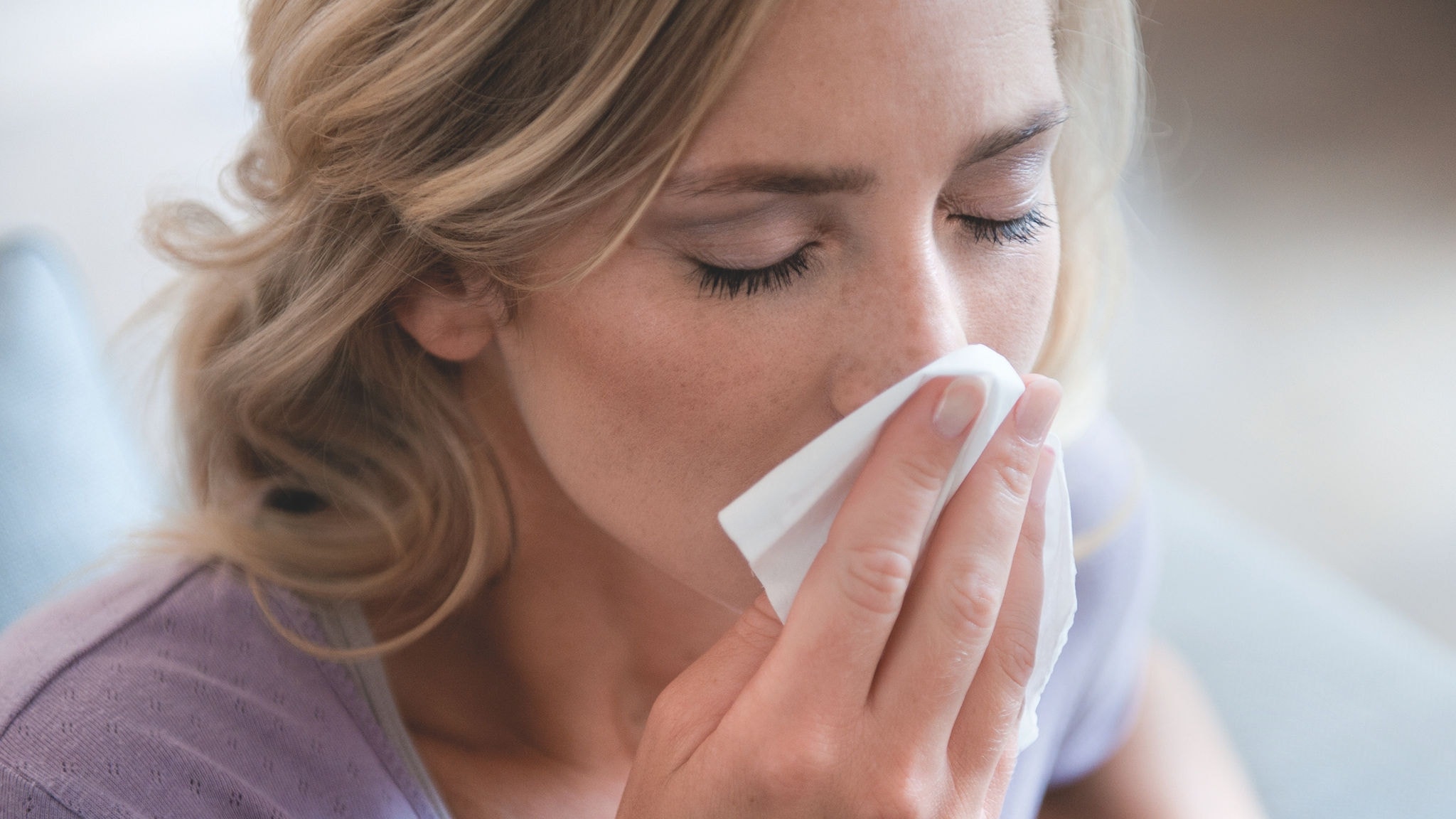 Žena si fúka nos, pretože ju trápi peľová alergia