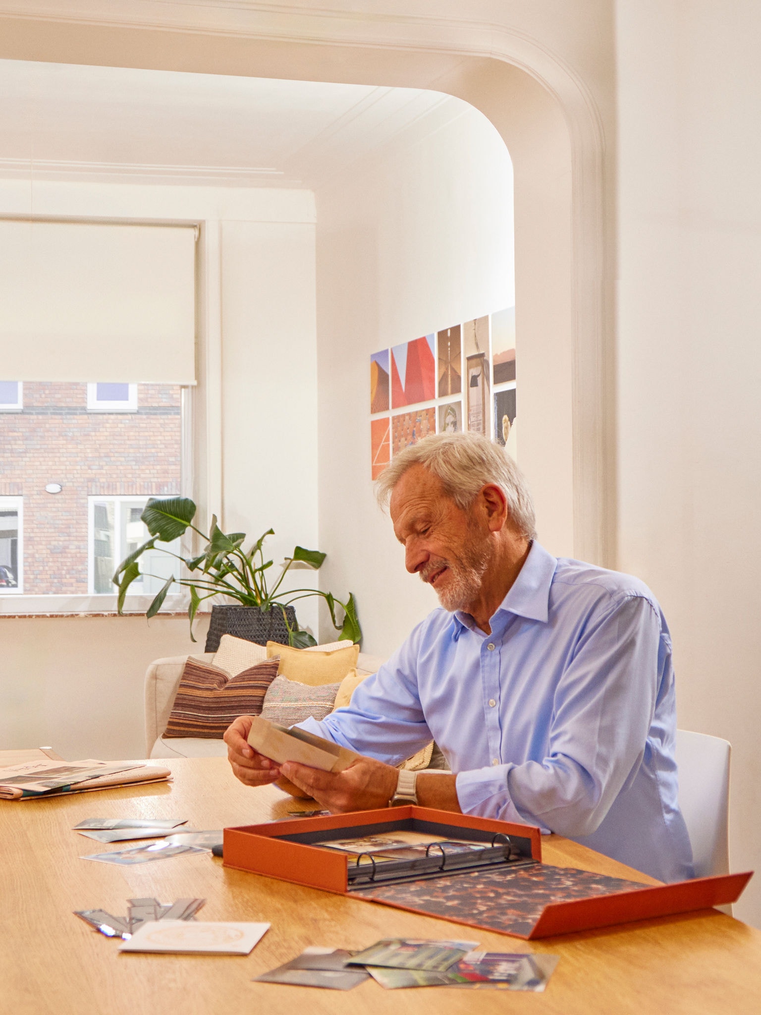 Muž sa nachádza pri stole s fotoalbumom v suchej, zdravej obývacej izbe vďaka vetraniu zabezpečujúcemu kontrolu vlhkosti