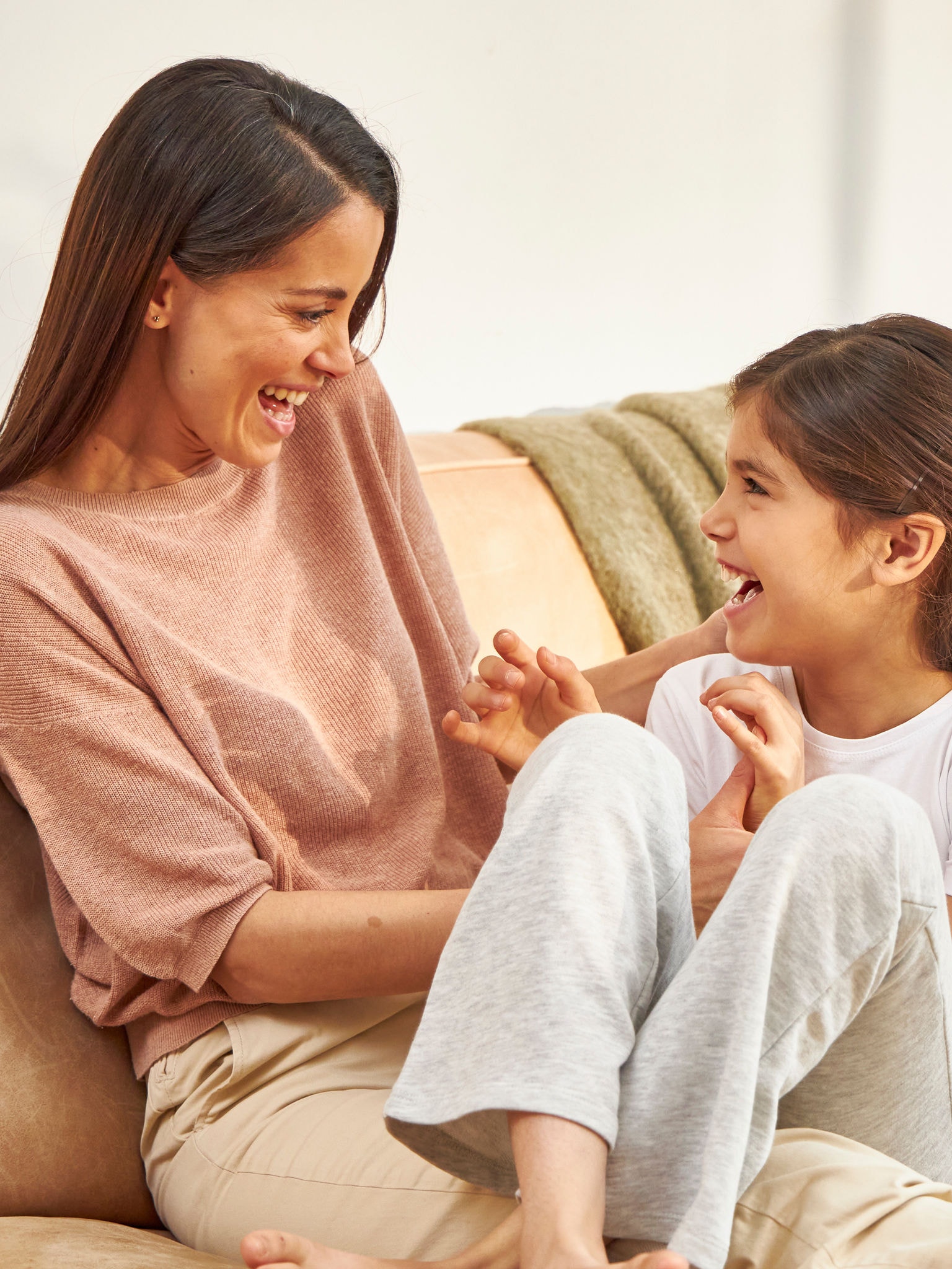 Matka s dcérou sa smejúc túlia na gauči