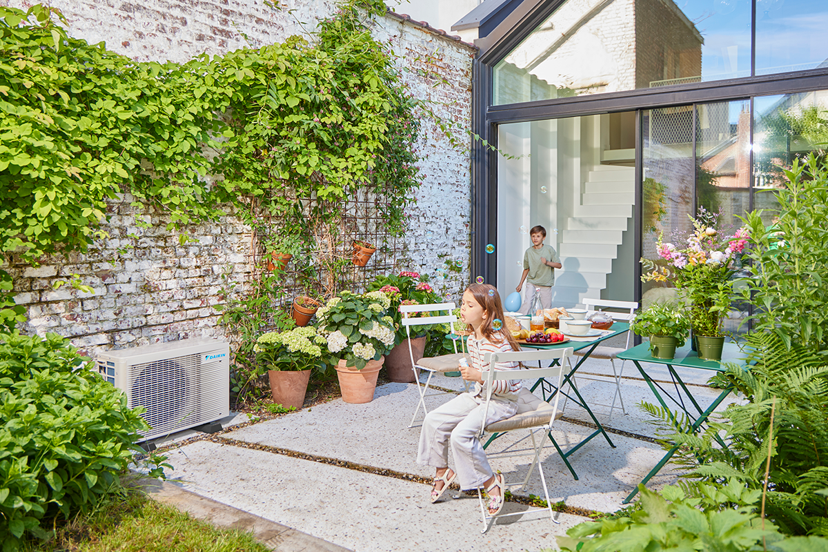 Deti sa hrajú s guličkami na záhradnej terase vedľa vonkajšej jednotky tepelného čerpadla