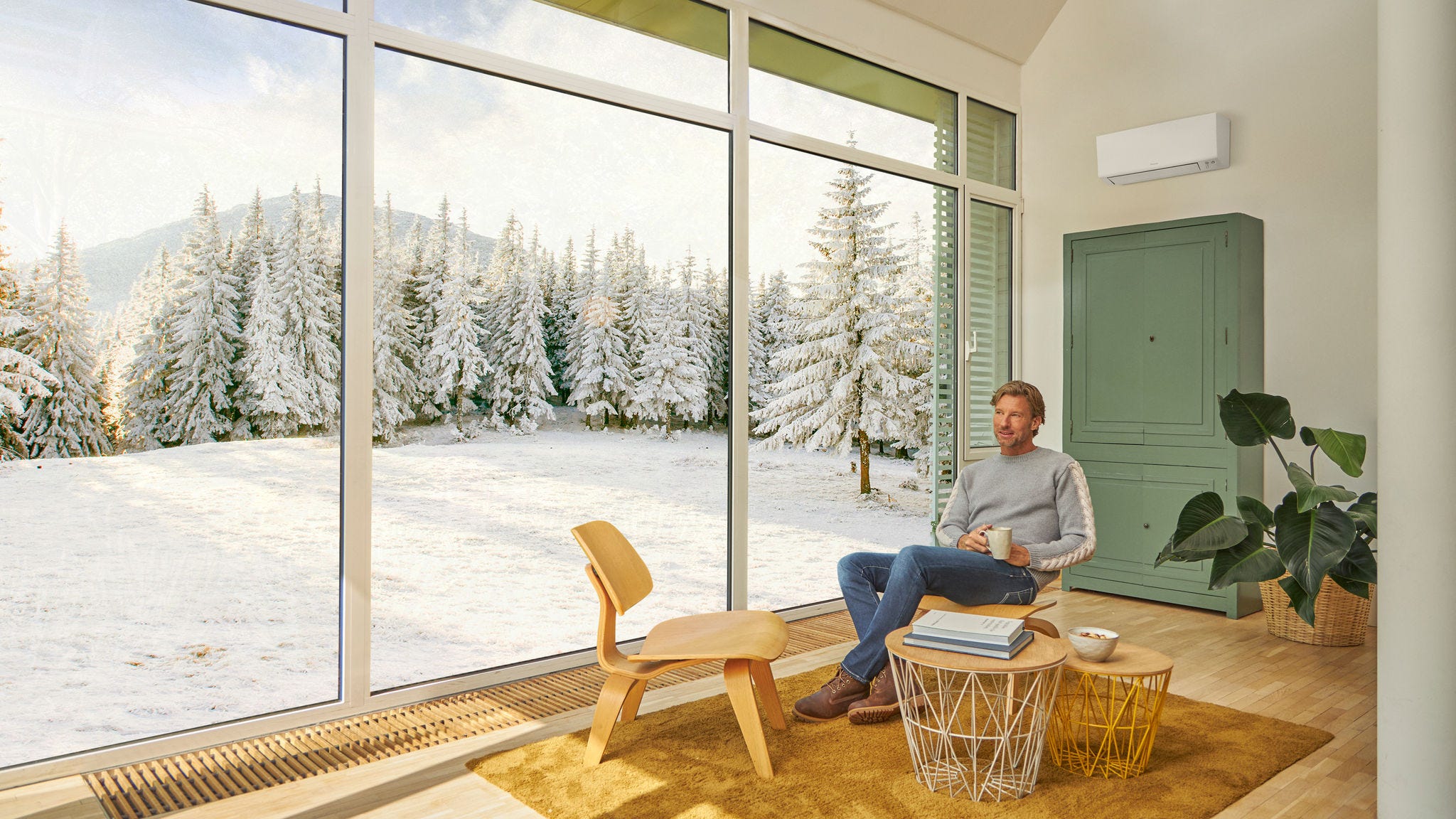 Muž sedí na gauči a užíva si vykurovanie pomocou klimatizácie