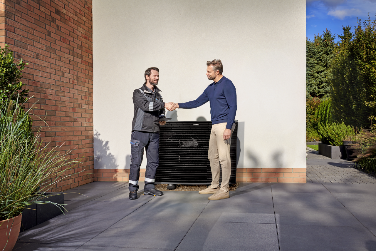 Inštalatér si podáva ruku so zákazníkom pred vonkajšou jednotkou Daikin Altherma